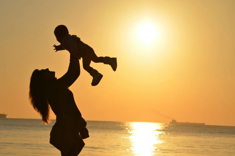 mère qui porte son enfant au coucher de soleil